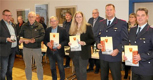 Bürgermeister Alf Hesse (l.) zeichnet langjährige ehrenamtlich Tätige aus (v.l.): Wolfgang Fricke, Günther Meyer, Sarah Schreiber, Oliver Bormann und Dennis Quadt. Für die Ehrung erheben sich die Ratsmitglieder von ihren Plätzen (Hintergrund).