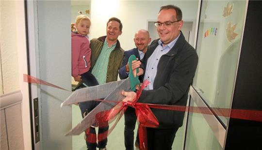 Bürgermeister Ingo Henze, Kita-Verband-Geschäftsführer Andreas Dlugos sowie Architekt Christian Spahn mit seiner Tochter (v.r.) durchschneiden symbolisch das Band zur Eröffnung des neuen Krippenanbaus.