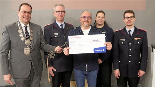 Bürgermeister Ingo Henze, Stadtbrandmeister Matthias Brunke (1. & 2. v.l.) und Ortsbrandmeister Stefan Rühmann (r.) freuen sich über den Scheck von Mike Scholz und Stefanie Schmidt.