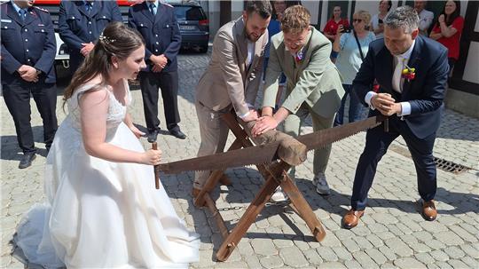 Bürgermeister Martin Schulze und seine Frau Kira Maria sägen traditionell einen Holzstamm durch.