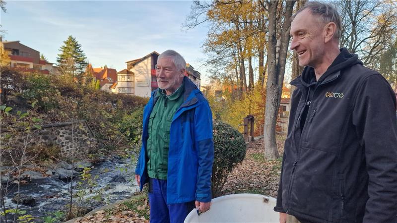Bad Harzburg entlässt 1000 Bachforellen in die Radau Bürgermeister von Bad Harzburg, Ralf Abrahms steht links, Fischwirtschaftsmeister Stephan Ohlendorf rechts, gemeinsam halten sie einen weißen Bottich in der Hand.