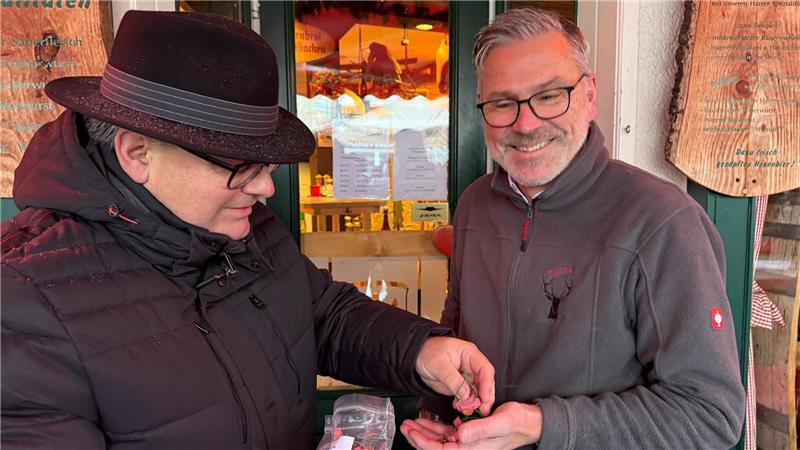 Ein Mann überreicht einem anderen kleine Glücksschweinchen.