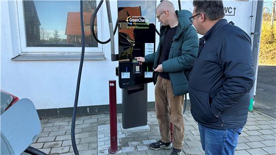 Bürgermeister Wolfgang Langer (rechts) beobachtet, wie Tobias Brabanski als einer der ersten seinen Wagen mit Strom aus der neuen Elektrotankstelle lädt.