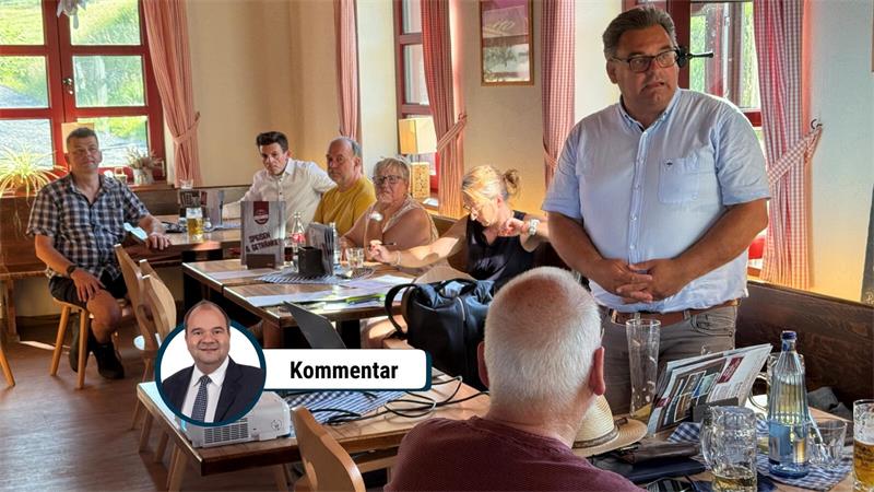 Mehrere Menschen sitzen in einem Raum voller Tische.