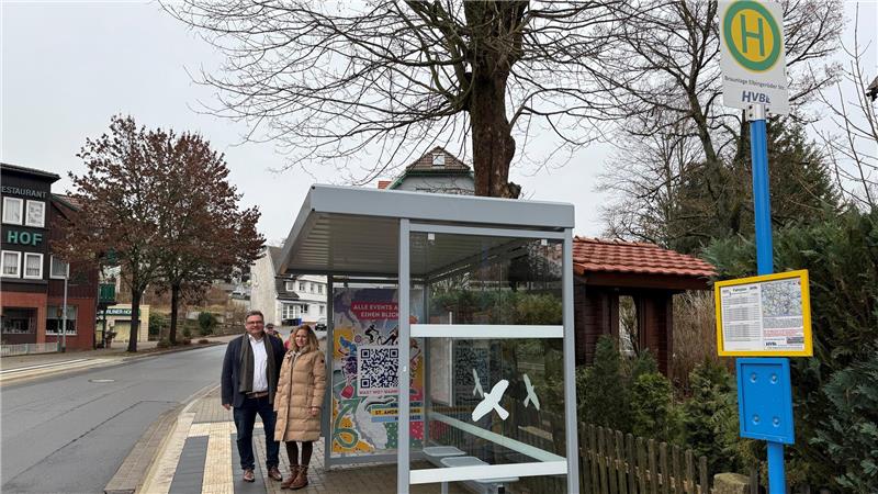 Eine Frau und ein Mann stehen an einem Bushäuschen.