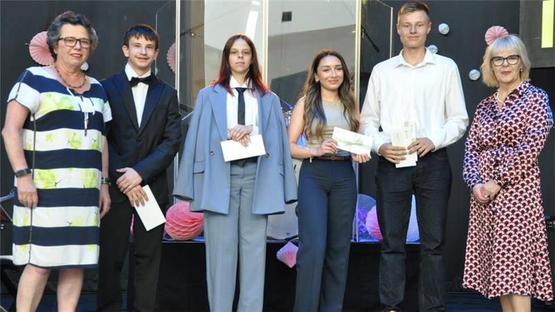Sechs Personen in festlicher Kleidung stehen nebeneinander und halten Urkunden oder Umschläge.