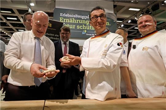 Bundesagrarminister Cem Özdemir und Berlins Regierender Bürgermeister Kai Wegner formen Brezeln beim Eröffnungsrundgang über das Messegelände der Grünen Woche.