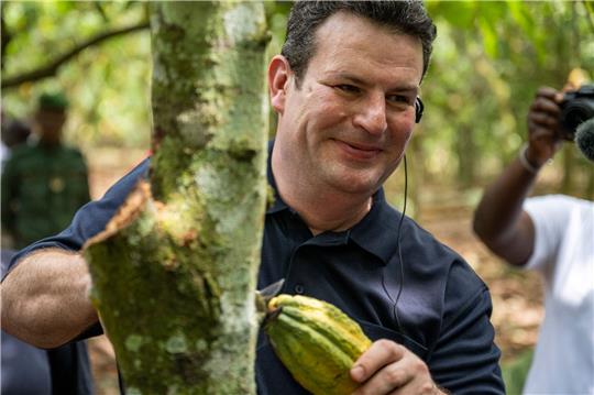 Bundesarbeitsminister Hubertus Heil erntet auf einer Kakaoplantage in Agboville an der Elfenbeinküste eine reife Kakao-Schote.