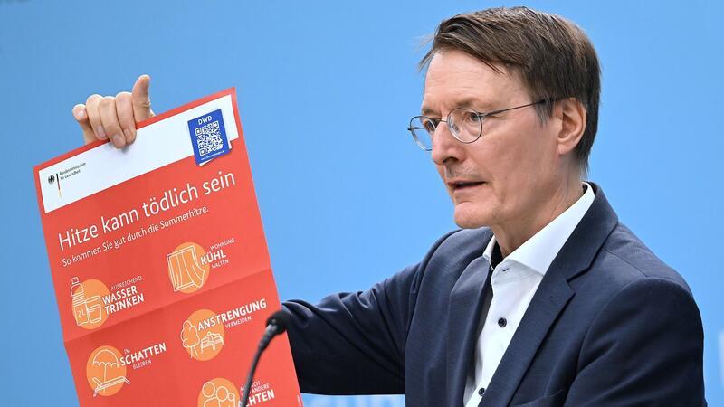 Bundesgesundheitsminister Karl Lauterbach (SPD) hält ein Plakat zum Thema Hitzeschutz hoch.