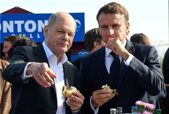 Bundeskanzler Olaf Scholz (SPD) und Frankreichs Präsident Emmanuel Macron (r) essen an der Elbe in Hamburg-Blankenese Fischbrötchen.