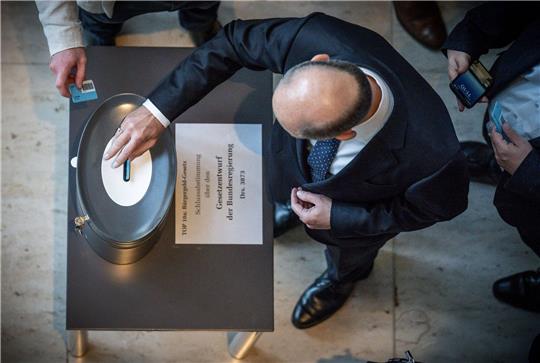 Bundeskanzler Olaf Scholz (SPD), wirft seine Stimmkarte zum Bürgergeld im Bundestag ein.