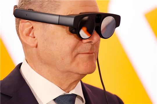 Bundeskanzler Olaf Scholz mit eier AR-Datenbrille (Augmented Reality) zur Prozessüberwachung einer Maschine.