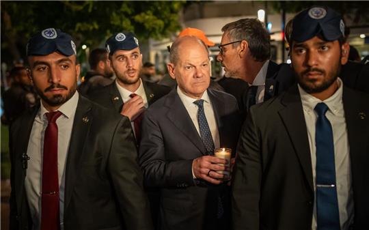 Bundeskanzler Olaf Scholz, umringt von Bodyguards, bei seinem Solidaritätsbesuch in Israel mit einer Kerze in der Hand am Dizengoff Square im Zentrum von Tel Aviv.