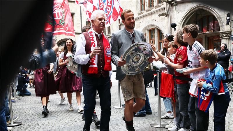 Bundesliga-Torschützenkönig Harry Kane trägt die Meisterschale flankiert von Oberbürgermeister Dieter Reiter (mit Fanschal) ins Münchner Rathaus.