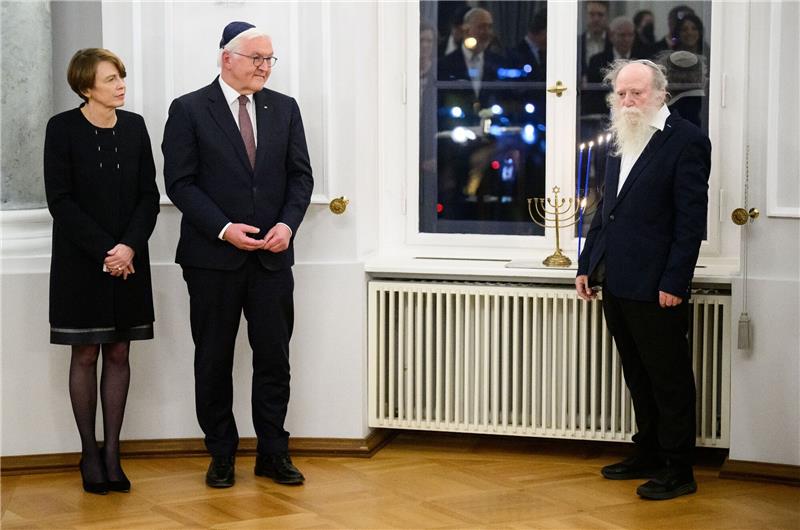Steinmeier: Chanukka-Feier mit Enkeln geflohener Familie Bundespräsident Frank-Walter Steinmeier und seine Frau Elke Büdenbender sowie Yehuda Mansbach (r), der Enkel von Rabbiner Arthur Posner, bei der gemeinsamen Chanukka-Feier im Schloss Bellevue. Auf der Fensterbank steht der Chanukka-Leuchter der Familie Posner.