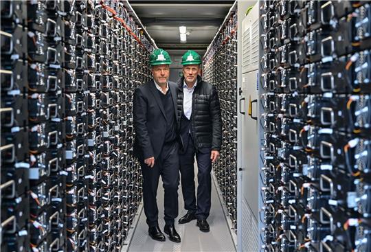 Bundeswirtschaftsminister Robert Habeck (l. Bündnis 90/Die Grünen) und Leag-Chef Thorsten Kramer stehen bei einem Rundgang über das Gelände vom Braunkohlekraftwerk Schwarze Pumpe in einem Batteriespeicher.