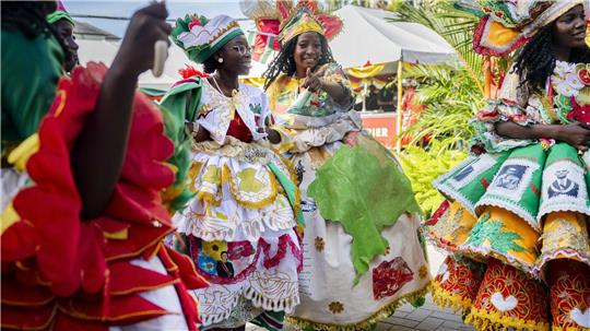 Bunt gekleidete Gäste feiern im Garten des Präsidentenpalastes von Suriname.