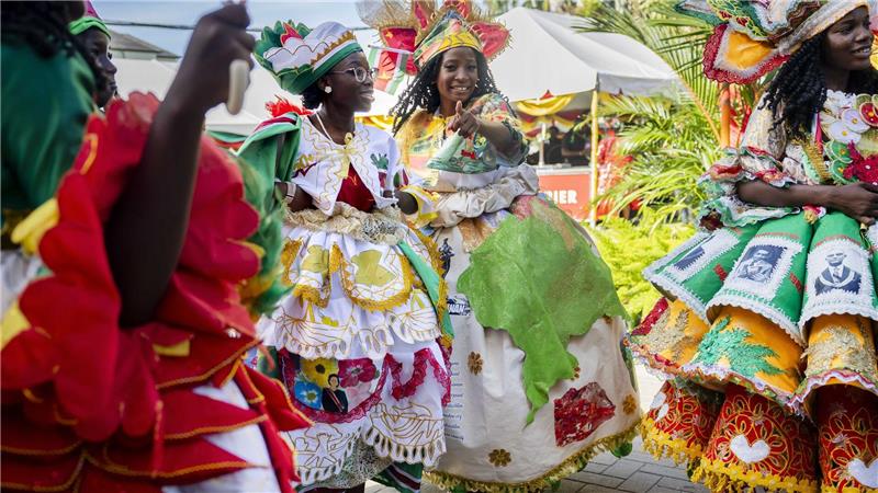 Bunt gekleidete Gäste feiern im Garten des Präsidentenpalastes von Suriname.