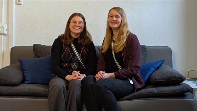 Caroline (l.) und Julia lächeln auf der Couch in der Studentinnenverbindung der TU .