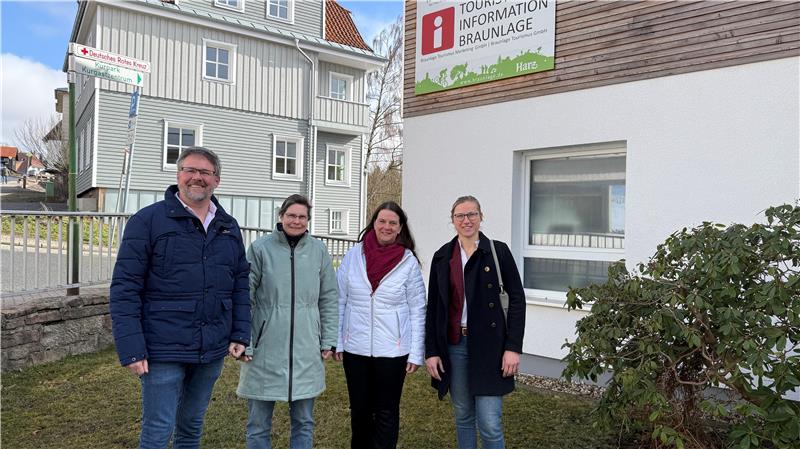 Das Bild zeigt drei Frauen und einen Mann vor einem Haus.