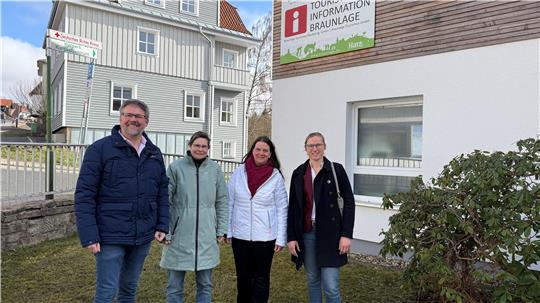Das Bild zeigt drei Frauen und einen Mann vor einem Haus.
