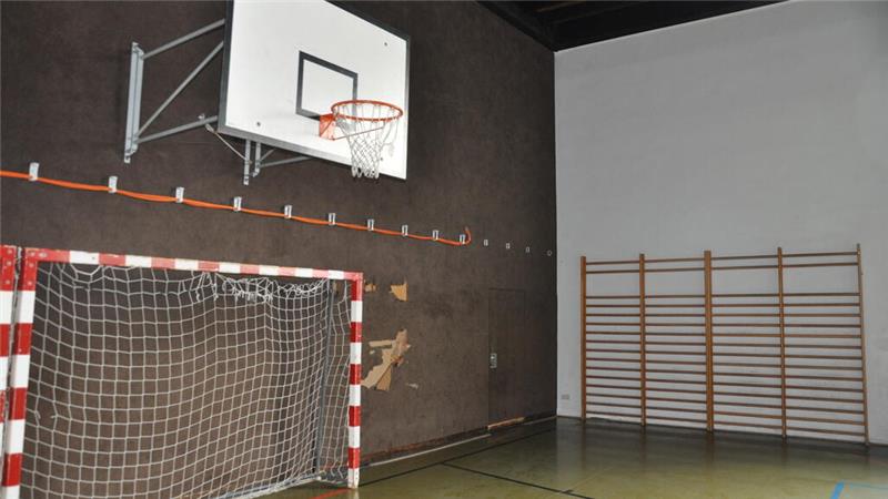 Basketballkorb über einem Handballtor in einer Sporthalle mit Sprossenwand an der Wand