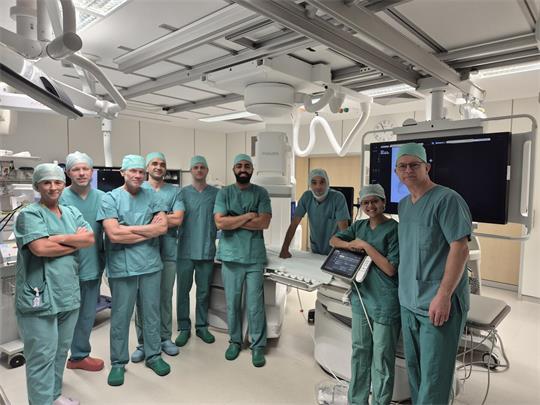 Mehrere Ärzte und medizinische Mitarbeiter in Krankenhauskleidung stehen vor einer neuen Anlage.
