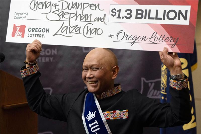 Cheng Saephan hält einen Riesencheck in Höhe von 1,3 Milliarden Dollar in die Höhe.