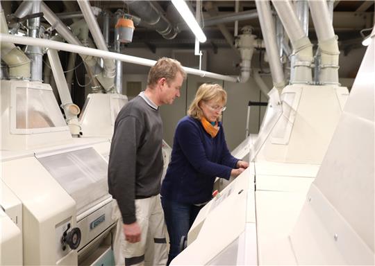 Christian Bammert und Anke Dege in der Walzenkammer, wo das Mehl vermahlen wird. Immer wieder wird dieser energieintensive Prozess kontrolliert. Foto: Neddermeier