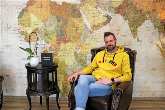 Claus Bernecker im Sessel vor der Weltkartenwand seines neu eröffneten Reisebüros im Fliegerhorst. Foto: Jenzora