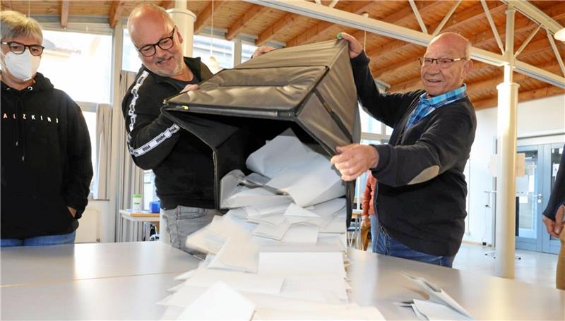 Wahlhelfer leeren eine Urne mit Stimmzetteln aus.