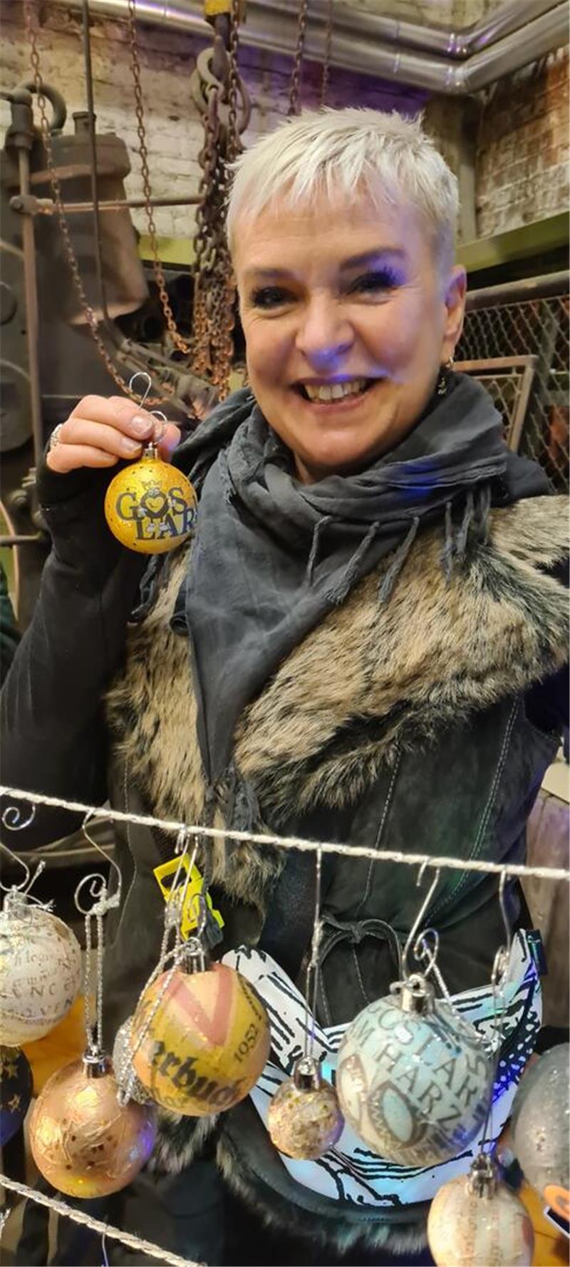 Großer Besucheransturm auf Goslars Weihnachtsmarkt unter Tage Eine Frau hält lachend eine Weihnachtsbaumkugel hoch, auf der Goslar steht.