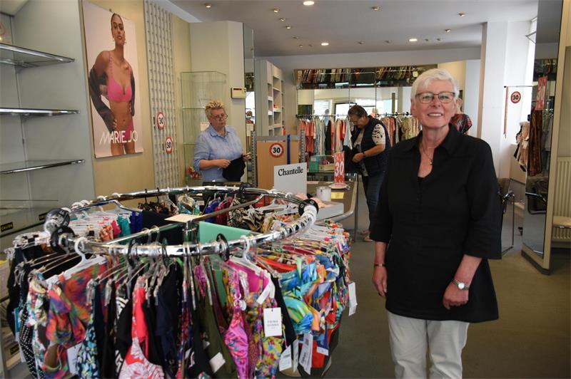 Eine Frau steht an einem Wäscheständer in einem Geschäft. 