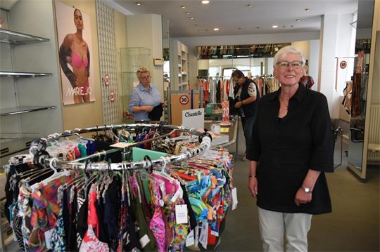 Eine Frau steht an einem Wäscheständer in einem Geschäft. 