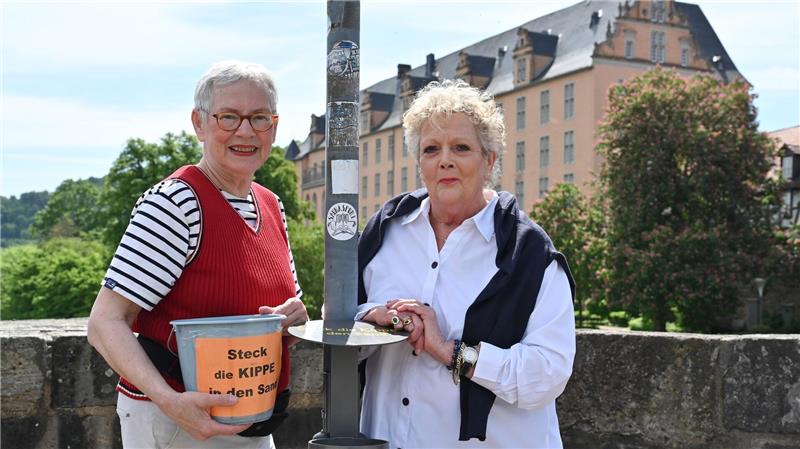Cornelia Schulze (l) und Heike Tauer-Schneider haben in einer Nacht und Nebelaktion Plastikeimer als Kippen-Mülleimer aufgestellt. Nun gibt es eine Dauerlösung.