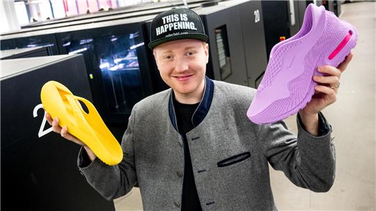 Cornelius Schmitt, CEO vom Schuhhersteller Zellerfeld, steht mit Schuhen aus dem 3D-Drucker in der Produktion vor Druckern. 