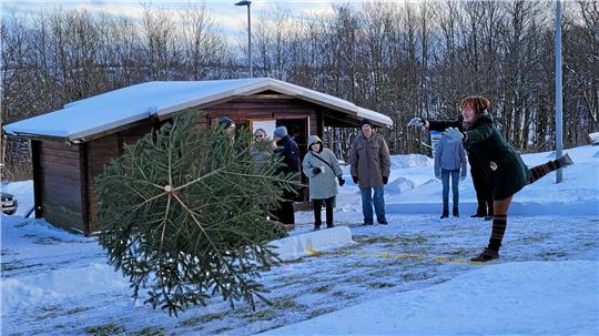 Eine Frau wirft einen Weihnachtsbaum von sich weg.