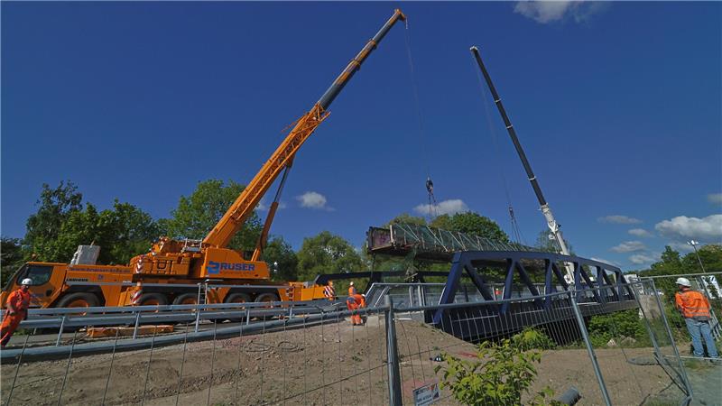 Da legt sie sich nieder: Zwei 180-Tonnen-Kräne platzieren die Behelfsbrücke zum Auseinanderbauen auf die neue Okerbrücke.