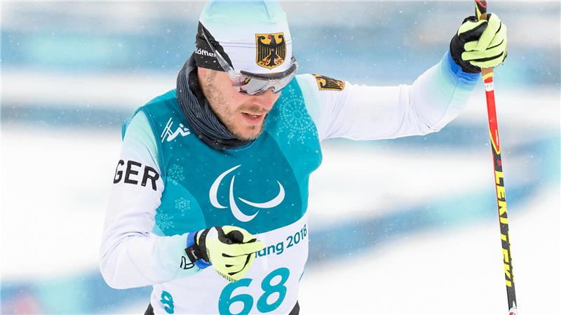 Langläufer mit Startnummer 68 und weiß-blauem Trikot bei einem Skiwettbewerb