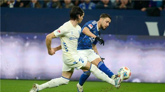 Das 1:0 für Schalke: Adil Aouchiche schießt, Magdeburgs Jean Hugonet fälscht mit der Fußspitze ab - und der Ball fliegt im hohen Bogen ins Tor. 