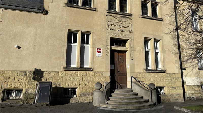 Fassade eines historischen Gebäudes mit steinerner Treppe, Holzportal und mehreren Fenstern.