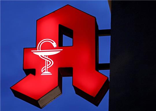 Das Apotheken-Logo leuchtet an einer Apotheke.