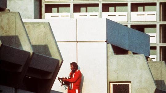 Das Archivbild vom 5. September 1972 zeigt einen bewaffneten Polizeibeamten im Trainingsanzug, der den Block im Olympischen Dorf in München abschirmt, in dem Terroristen israelische Sportler der Sommerspiele festhielten.