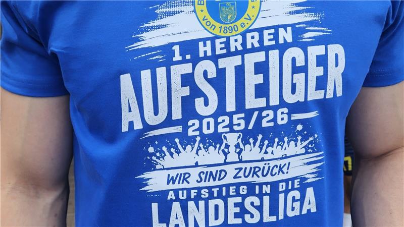 Oberkörper eines Mannes in blauem T-Shirt mit Aufdruck 'TSG Bad Harzburg von 1890 e.V. 1. Herren Aufsteiger 2025/26 Wir sind zurück Aufstieg in die Landesliga' 