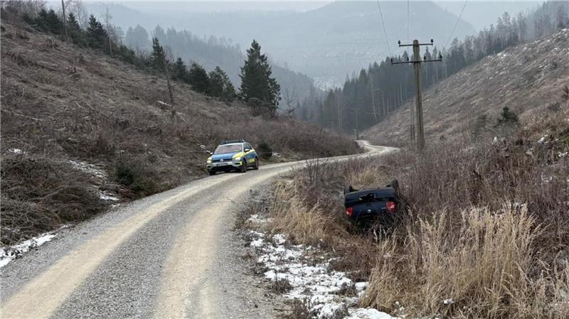 Das Auto liegt auf dem Dach im Graben, daneben steht ein Polizeiauto.