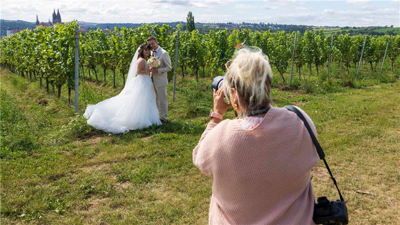 Das Brautpaar Isabell und Stephan lässt sich im Weinberg fotografieren.