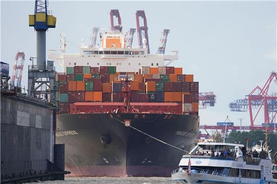 Das Containerschiff „Prague Express“ der Reederei Hapag-Lloyd wird von Schleppern an einen Containerterminal im Hafen gezogen.