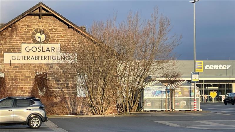 Altes Backsteingebäude mit der Aufschrift 'GOSLAR GÜTERABFERTIGUNG' neben einem Parkplatz und einem modernen Einkaufszentrum mit dem Schriftzug 'center'