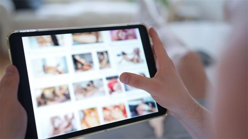 Hand hält Tablet mit unscharfen Miniaturbildern auf dem Bildschirm, andere Hand zeigt darauf