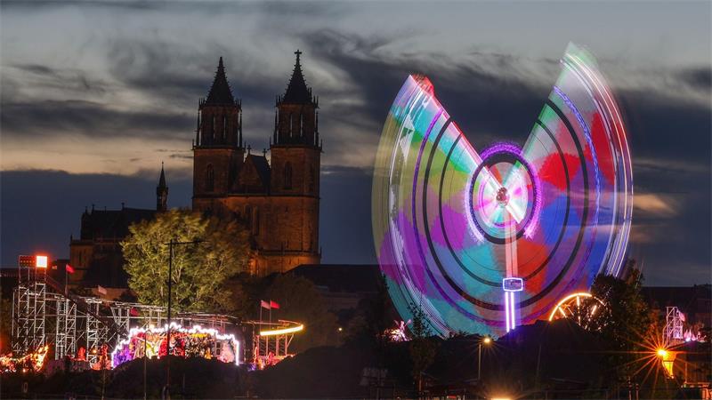Das Fahrgeschäft „Eclipse“ dreht sich am Abend vor dem Magdeburger Dom auf der 1016. Magdeburger Herbstmesse.